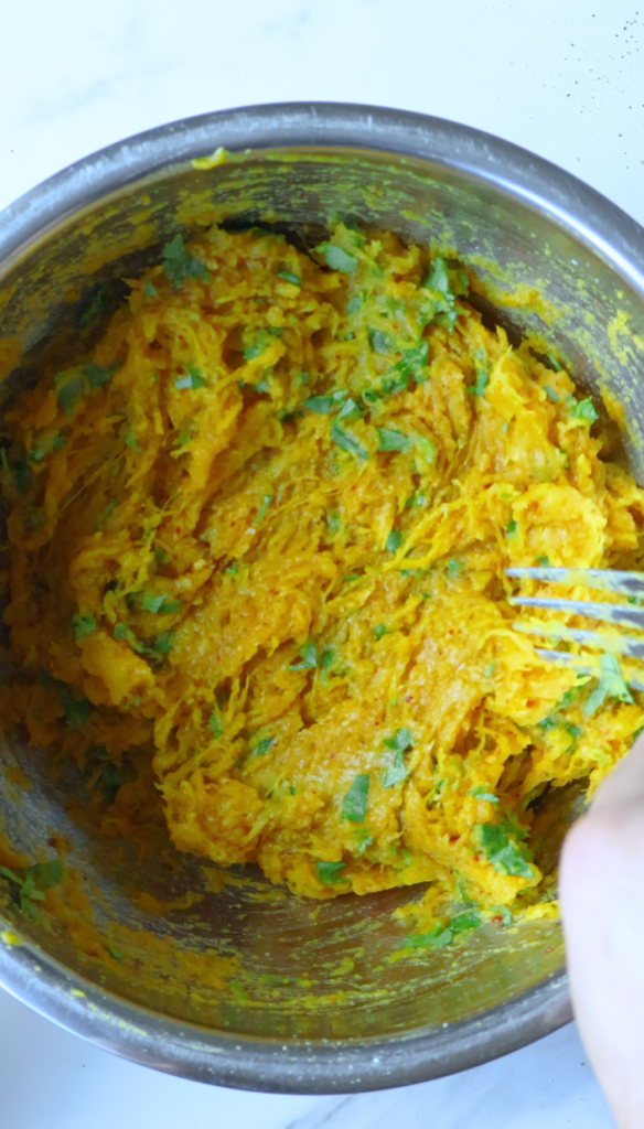 Remove the skin from your baked pumpkin, then mash pumpkin with chopped cilantro, black pepper, red chili flakes, coriander, garlic powder and salt.